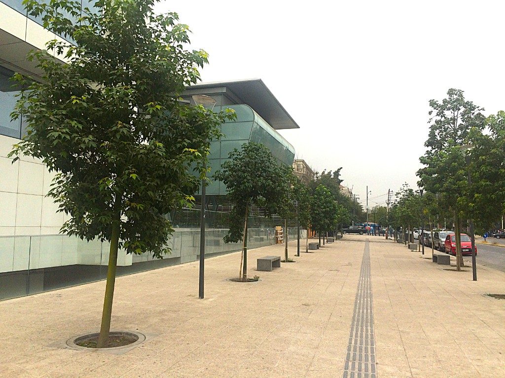 Vereda arbolada con bancas junto a un edificio